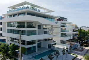 Modern apartment building with concrete exterior and rooftop terrace.
