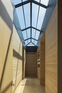 Modern corridor with wooden walls and a transparent roof featuring a skylight.