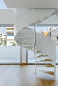 A modern metal staircase with perforated railings and wooden steps, set against a bright, airy background.