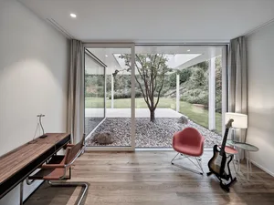 A modern minimalist office space featuring a wooden floor, minimalist furniture, and a connection to a serene outdoor area wi