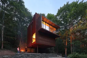 A modern residential interior with a wooden exterior on a forested hillside.