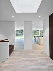 Interior view of a modern kitchen and dining area with marble floors and white walls.