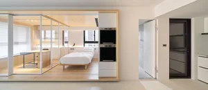 A modern minimalist bedroom featuring a bed with white sheets, wooden flooring, glass walls, and metal accents.