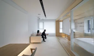 People sitting on a white sofa in a minimalist living room with wooden accents.