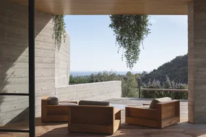 A modern living space featuring wood, concrete, and glass materials with an outdoor view.