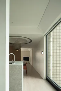 Modern residential interior with minimalist design, featuring a light-colored floor, white walls, and a sleek kitchen counter