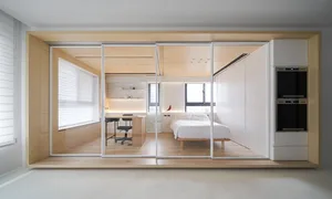 Modern minimalist bedroom featuring a white bed with wooden walls and furniture.