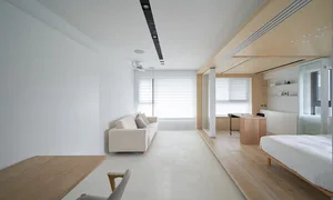 Minimalist living room featuring white furniture, wood accents, and large windows with sheer curtains.
