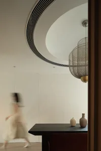 A modern minimalist living space featuring a metal chandelier and minimalist decor.