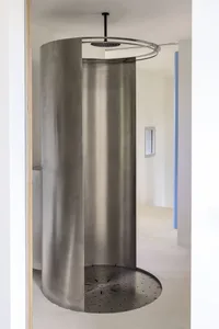 A minimalist, industrial-style bathroom shower with a metallic finish and geometric design elements.