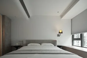 Minimalist bedroom with textured fabric bed, wood headboard, and glass window