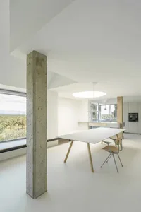 現代極簡住宅空間，展現裸露混凝土與大型玻璃窗。