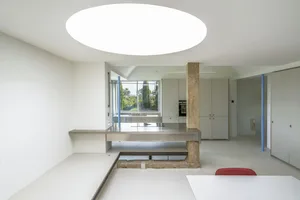 Modern kitchen interior featuring minimalist design with concrete countertops and white walls and flooring.