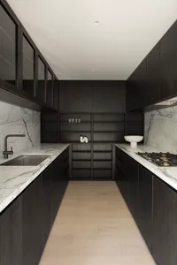Modern kitchen with marble countertops, dark wooden cabinets, and stainless steel appliances.