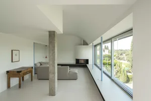Modern living room with concrete and glass elements, featuring a minimalistic design