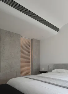 A modern minimalist bedroom featuring concrete walls, white furniture, and white blinds.