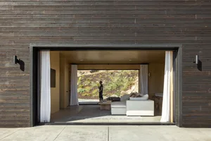 A modern living room with white furniture and a view of a rocky hillside.