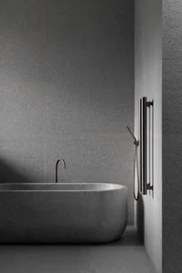 A minimalist industrial bathroom with grey granite bathtub and walls