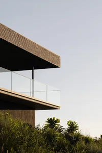 Modern house with glass and brick exterior, featuring a large balcony.