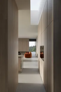 An interior view of a minimalist living room featuring wooden panelling and a bright orange sofa.
