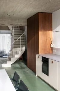 A modern kitchen with concrete flooring and wooden cabinets.