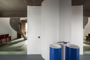 A modern interior with a concrete wall and blue cylindrical sinks.