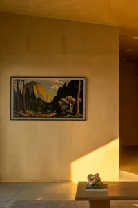 A modern interior space featuring wooden walls and a framed painting of a mountain landscape.