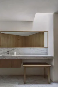 A modern bathroom with marble countertop, wooden accents, and a sink with a marble backsplash.