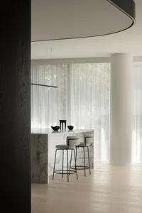 A modern kitchen interior featuring a marble counter and wooden stools.