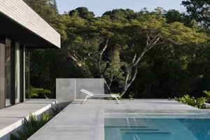 Modern patio featuring concrete flooring and minimalist design with a backdrop of lush greenery.
