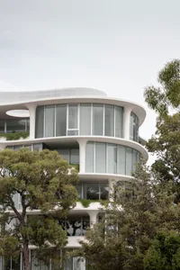 A modern residential building with glass walls and a white concrete facade.