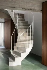 A modern, minimalist staircase constructed from concrete with white railings.