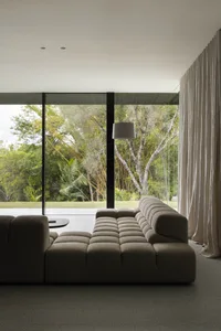 Modern living room with a textured couch and glass windows overlooking greenery.