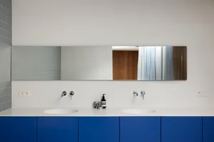 Minimalist bathroom with blue cabinets, metallic faucets, and wood accents.