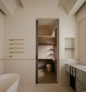 A minimalist bathroom featuring ceramic, marble, and brass elements.