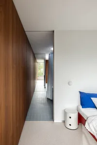 Minimalist bedroom with wooden walls and white floor and bedding.