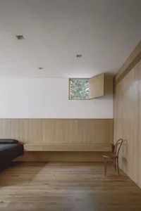 Minimalist bedroom featuring light-colored wooden paneling and a small window