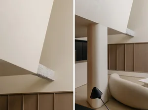Minimalist living room interior with concrete column, wood paneling, and white and beige tones.