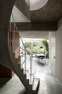 Modern interior design featuring a concrete staircase and floor, with a view of the garden through large windows.