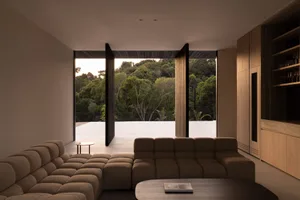 A modern living room with wood accents and large windows overlooking a lush green landscape.