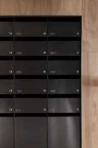 Black metal mailboxes on a wooden wall