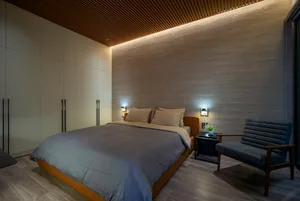 Minimalist bedroom with wood accents, including a textured wall, wood floors, and a wooden chair.