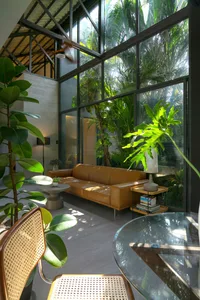 Modern minimalist living room featuring a brown leather sofa, green plants, and natural wood elements.