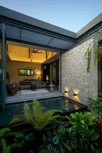 Modern living room featuring a natural stone accent wall and a cozy seating area with plants.
