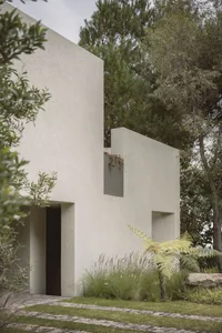 A minimalist modern exterior house with a concrete facade and greenery surrounding it.