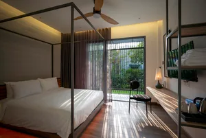 A modern bedroom with a wooden floor, a canopy bed, and a chair.