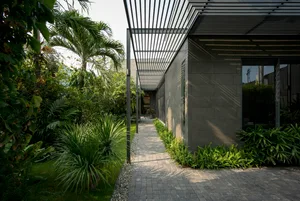 A modern house exterior featuring a brick wall, concrete patio, and lush greenery.