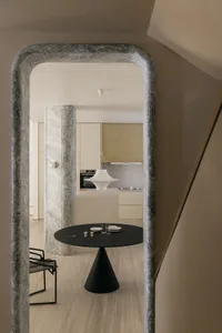A modern interior space featuring marble and concrete materials with a minimalist dining table and pendant light.