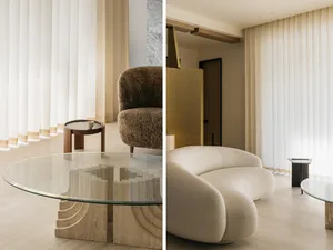 Modern living room featuring a minimalist couch, glass coffee table, and vertical blinds.