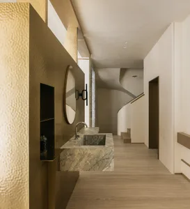 A modern bathroom with a marble countertop and brass vertical accents.
